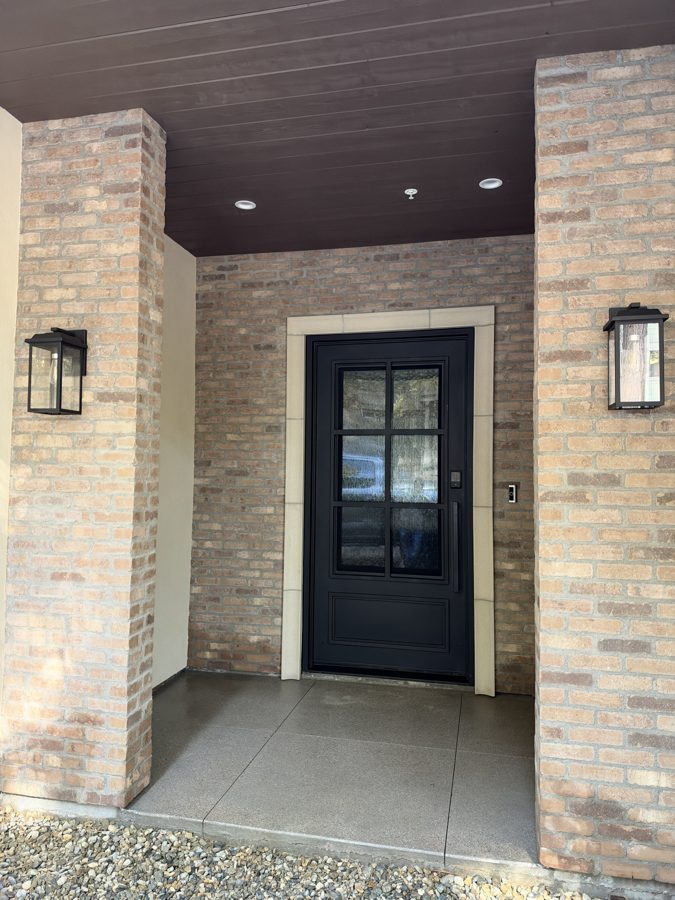 Clubhouse entry with a black glazed door and brick columns